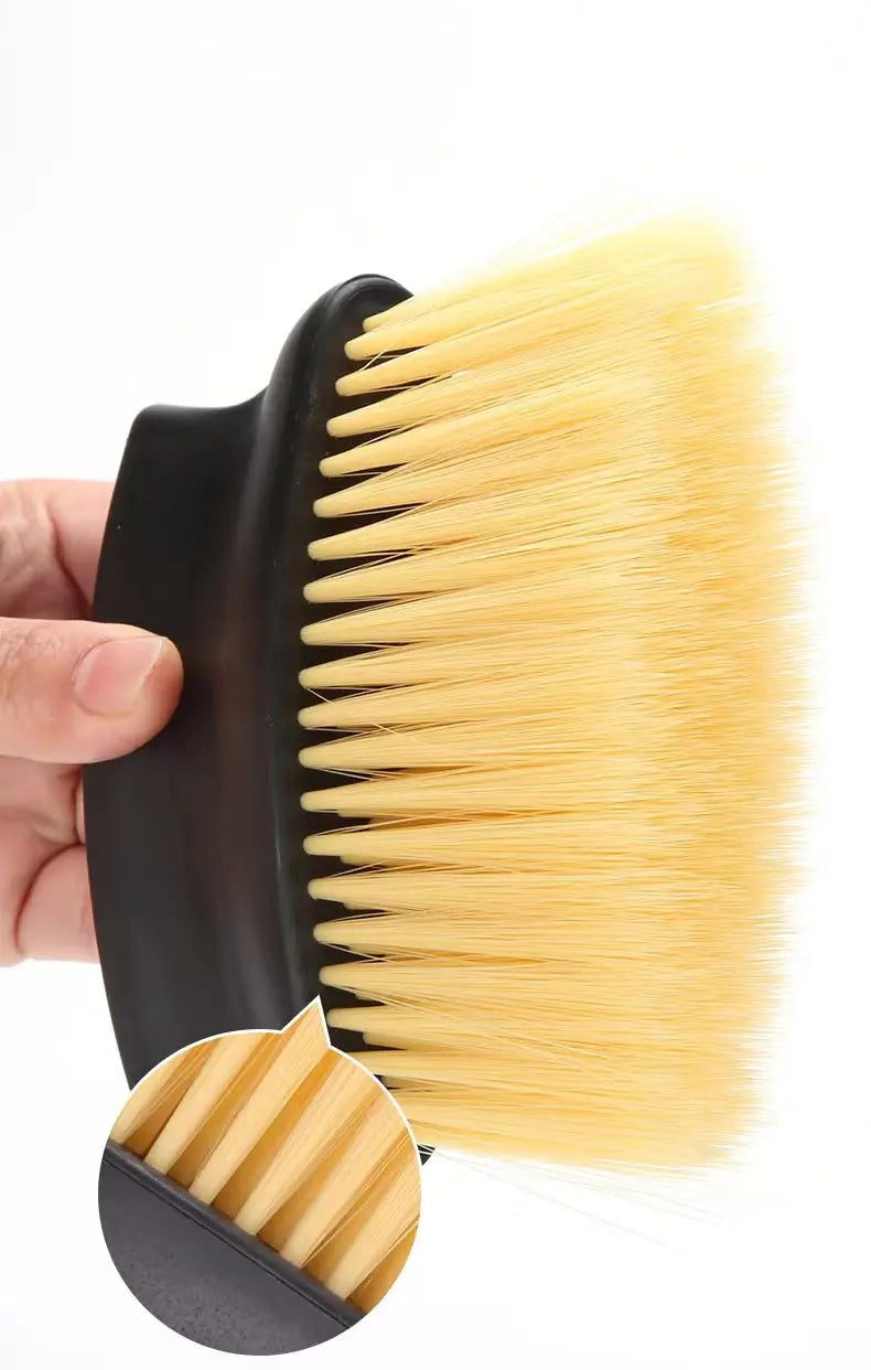 Black-handled brush with yellow bristles held by a hand against a white background