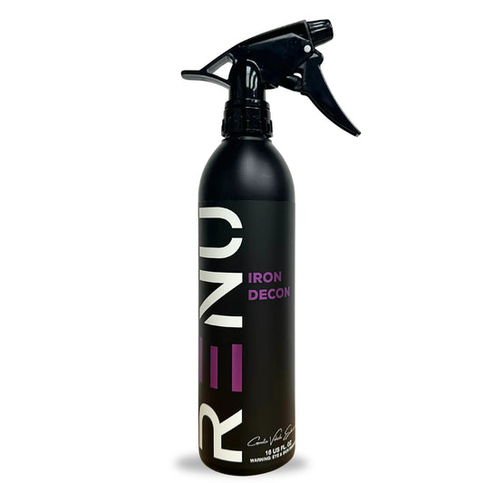 A black spray bottle of RENO Iron Decolorant with a black trigger sprayer, featuring white and purple branding on a white background.