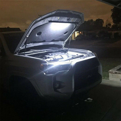 Car with open hood illuminated by a light at night