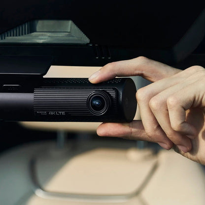 Hand adjusting the BlackVue DR970X LTE Plus II on a windshield