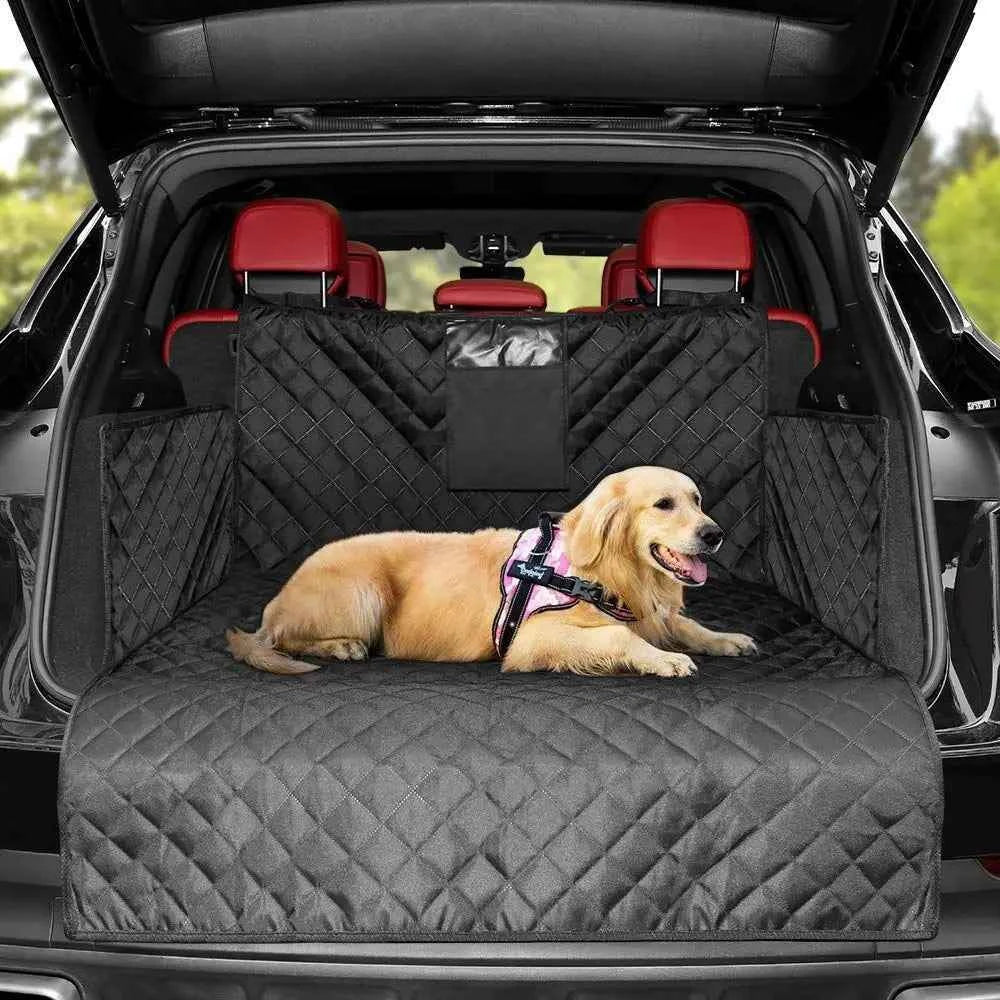 Dog sitting on a black quilted car bench cover in the back of a vehicle.