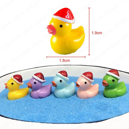 Five small rubber duckies wearing red Santa hats arranged in blue sand, with one yellow duckie shown above with red dimension lines indicating 1.8cm width and 1.