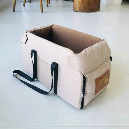 Beige pet carrier with black straps on a light gray floor