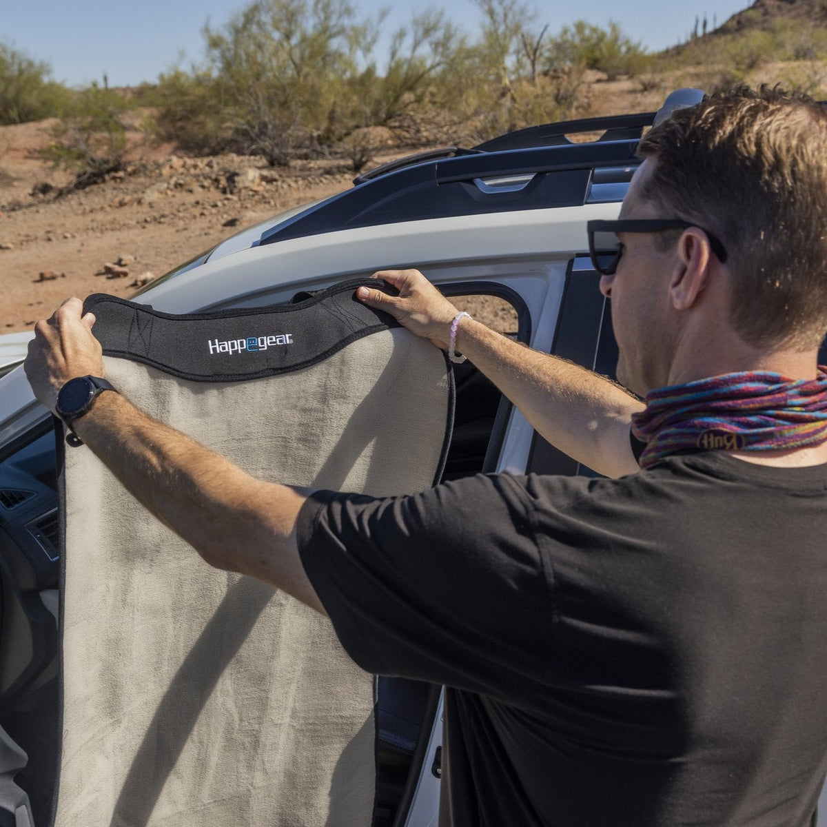 Person positioning a Happeseat cover over a vehicle seat outdoors