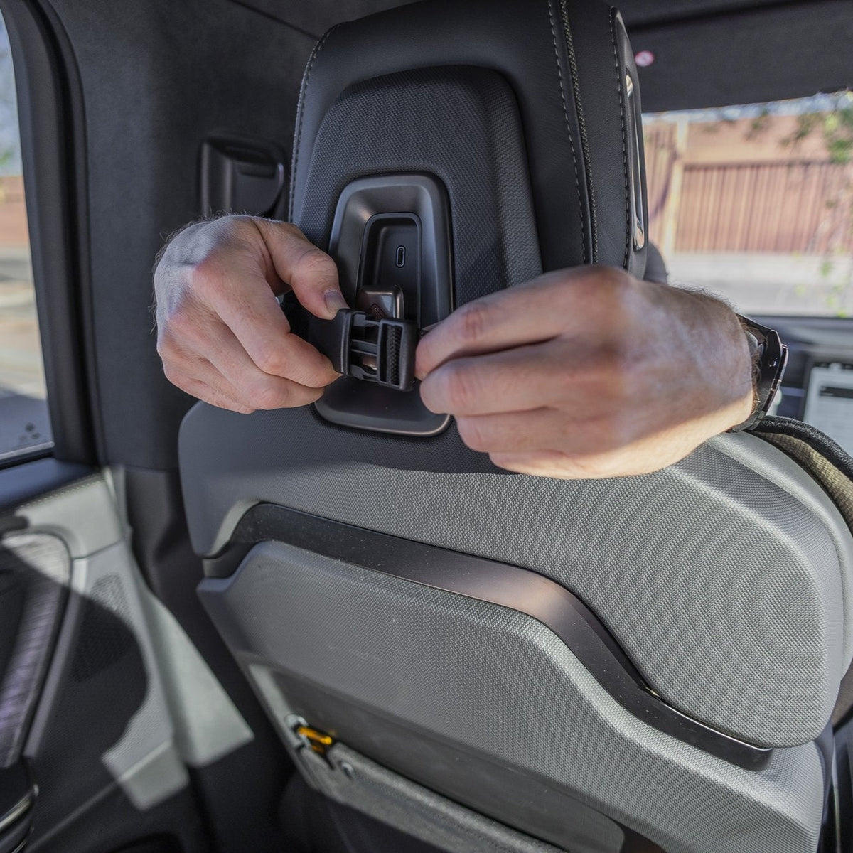 Close-up of hands fastening the Happeseat attachment buckle behind a seat