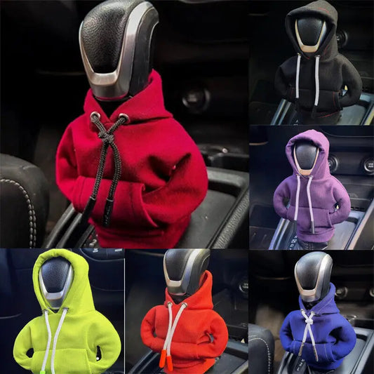 Six small hooded figures displayed in a 2x3 grid, each wearing a different hoodie color: red, black, purple, lime green, red-orange, and blue. The figures are posed inside cars around a gear shift console, with the shift knob visible above each hoodie.