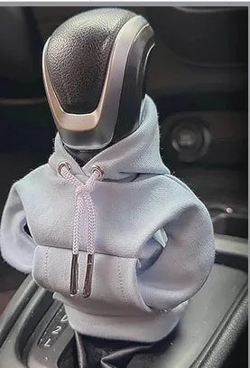 Car gear shift knob with a gray hoodie over it, inside a vehicle.
