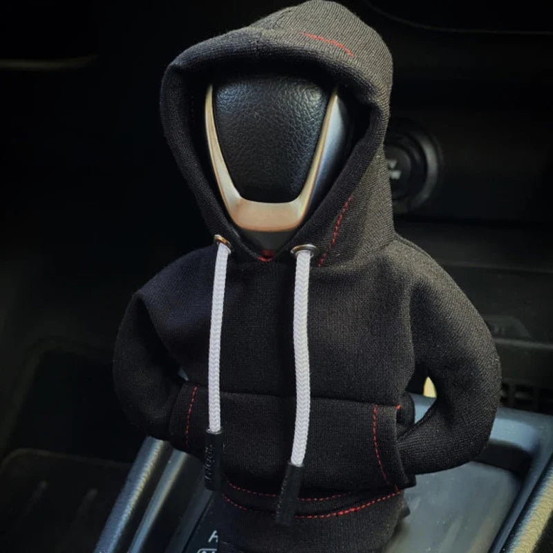 Car gear shift knob covered with a black hoodie inside a vehicle.