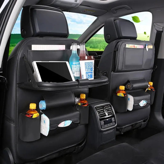 Car interior with black organizer attached to back seat holding drinks, snacks, and a tablet.