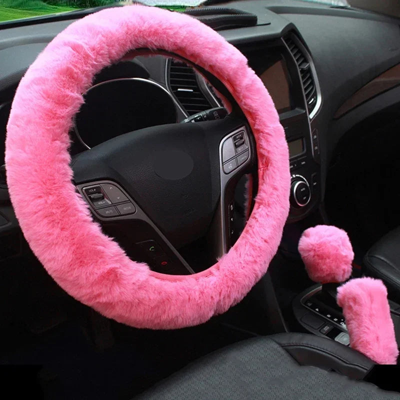 Pink fuzzy steering wheel cover and gear shift cover on a car dashboard.