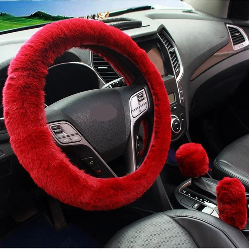 Red fuzzy steering wheel cover and gear shift cover on a car dashboard.