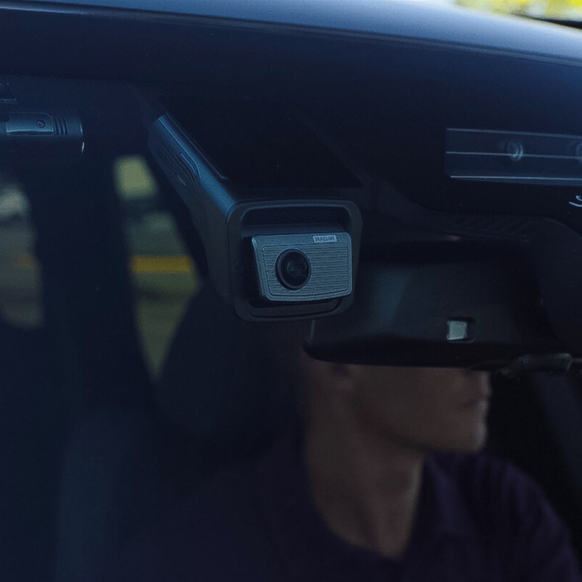 Person sitting inside a vehicle with a camera mounted on the dashboard.