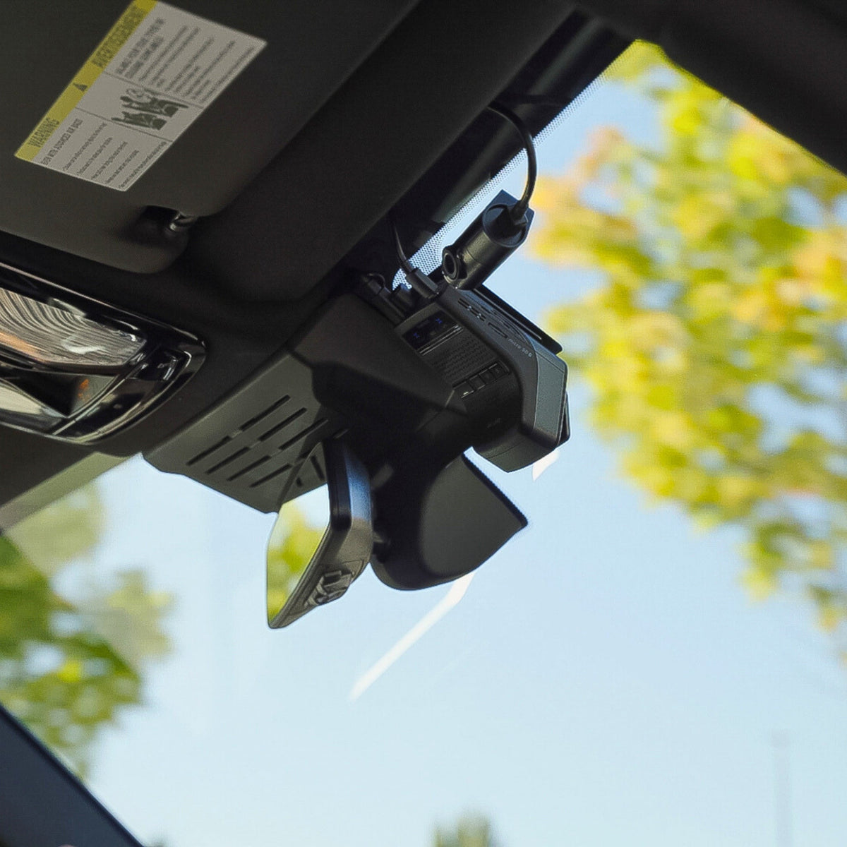 Car sun visor with a mounted device against a blurred outdoor background