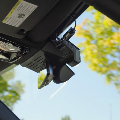 Car sun visor with a mounted device against a blurred outdoor background
